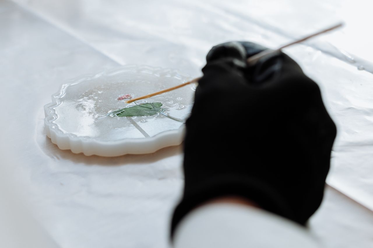 About Close-up of hands crafting detailed resin art using a delicate tool, showcasing artistic precision.